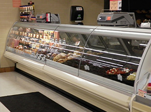 A deli case with meat and vegetables on it.